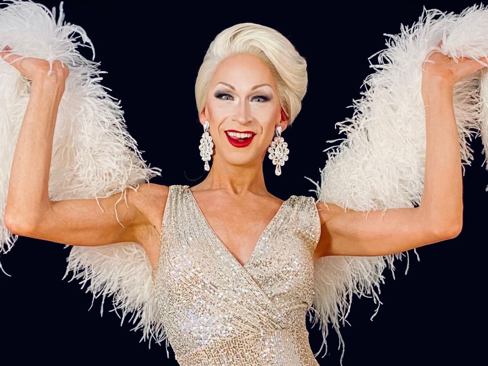 Drag-Queen mit weißem Feder-Schal und weiß, glitzerndem Kleid